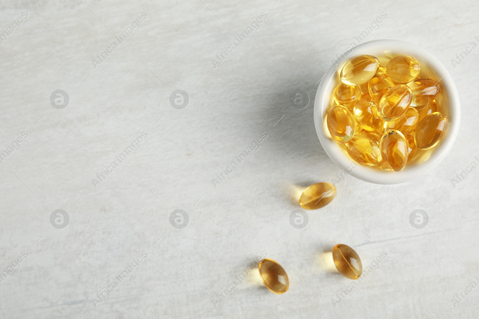 Photo of Bowl with cod liver oil pills and space for text on light background, flat lay
