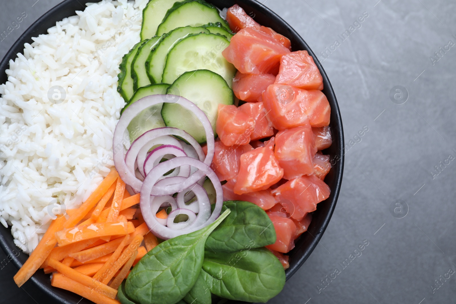 Photo of Delicious poke bowl with salmon and vegetables on grey table, top view