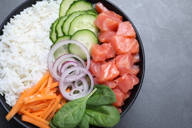 Delicious poke bowl with salmon and vegetables on grey table, top view