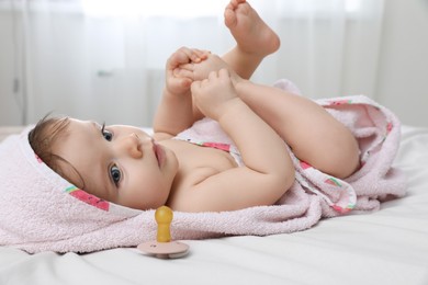 Cute little baby in hooded towel after bathing on bed at home