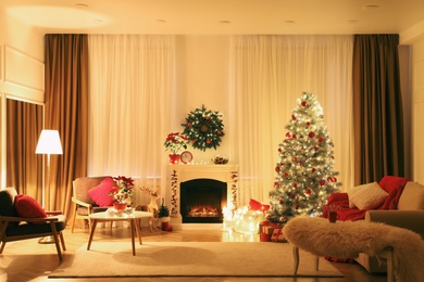 Photo of Beautiful living room interior with burning fireplace and Christmas tree in evening