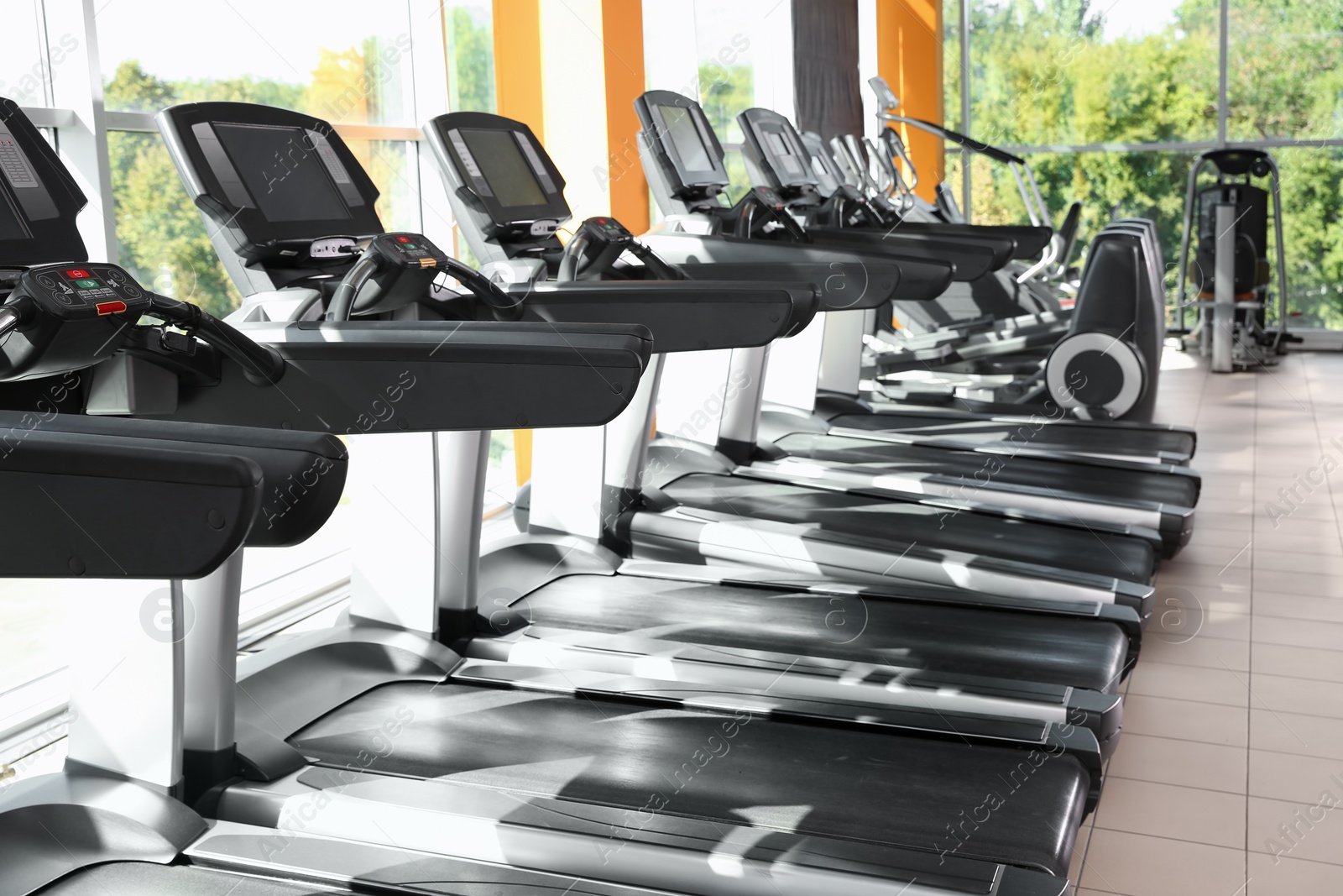 Photo of Gym interior with row of treadmills near windows