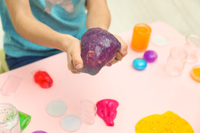 Photo of Girl holding purple slime over table, closeup