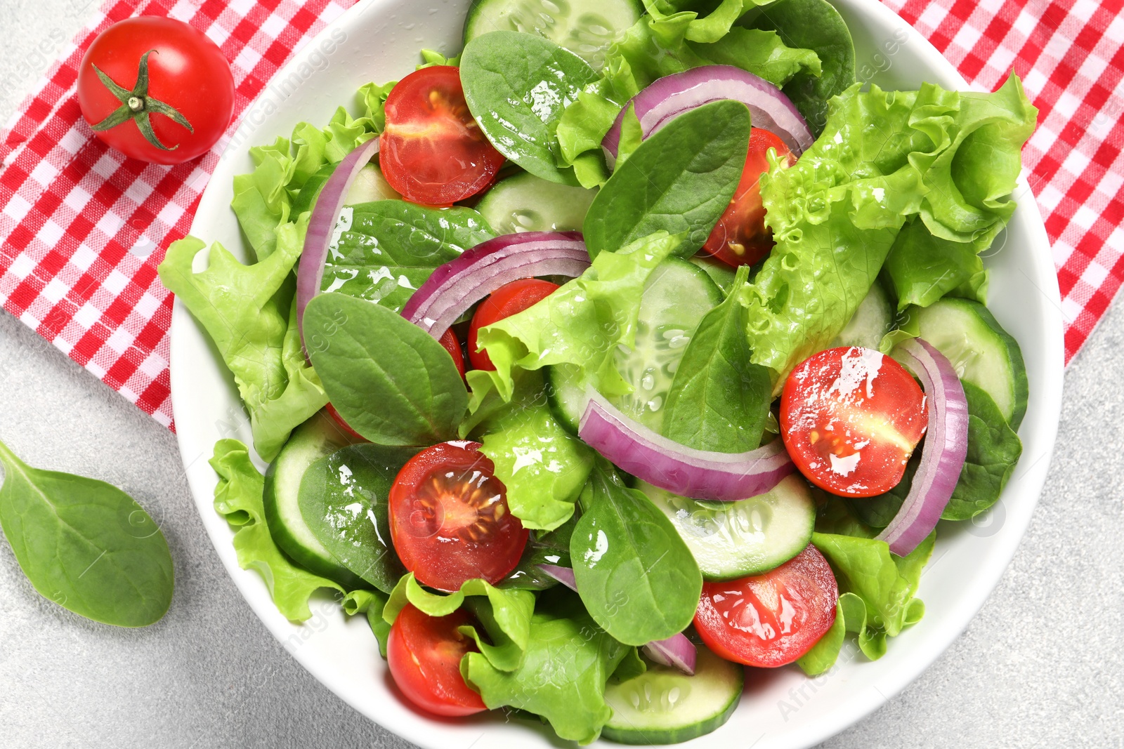 Photo of Delicious vegetable salad on light grey table, flat lay