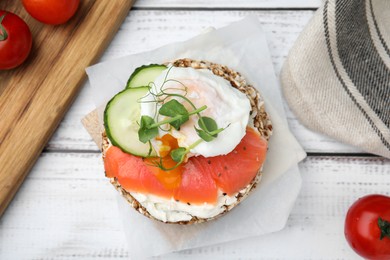 Photo of Crunchy buckwheat cakes with salmon, poached egg and cucumber slices on white wooden table, flat lay