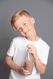 Photo of Little boy with glass of milk shake on grey background