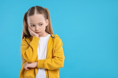 Photo of Portrait of sad girl on light blue background, space for text