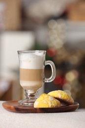 Aromatic latte macchiato in glass and cookies on white table against blurred background