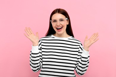 Portrait of emotional woman in stylish eyeglasses on pink background