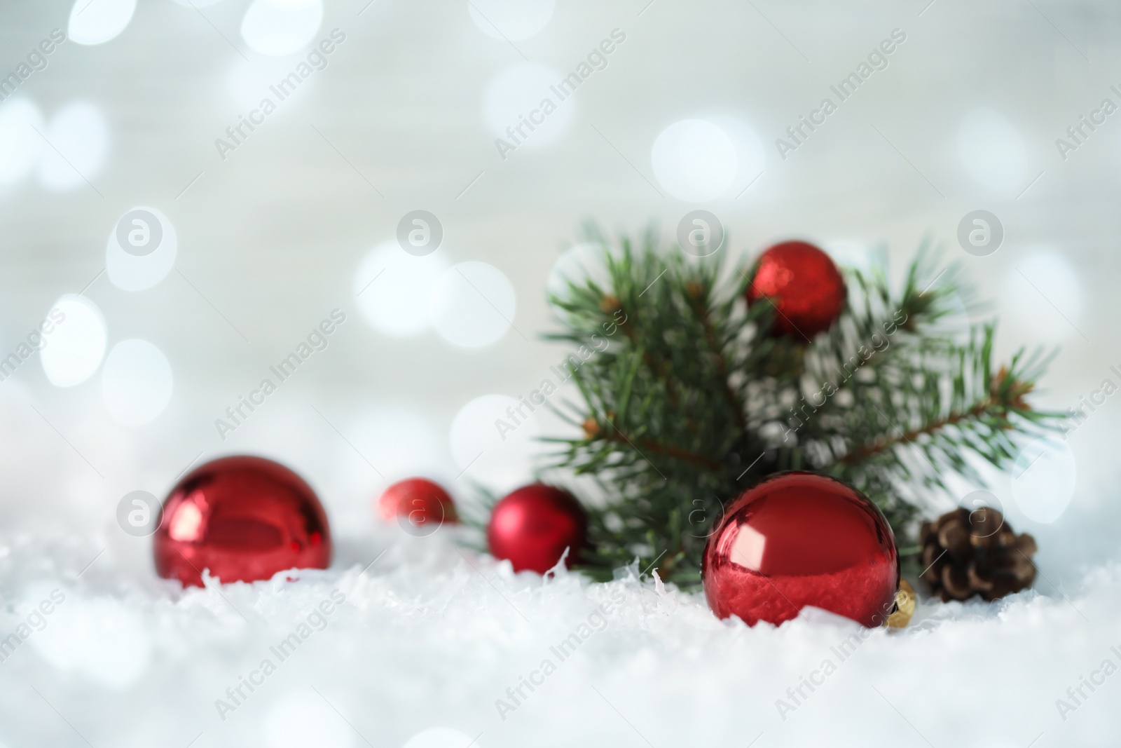 Image of Beautiful red Christmas balls and fir tree branch on snow, bokeh effect