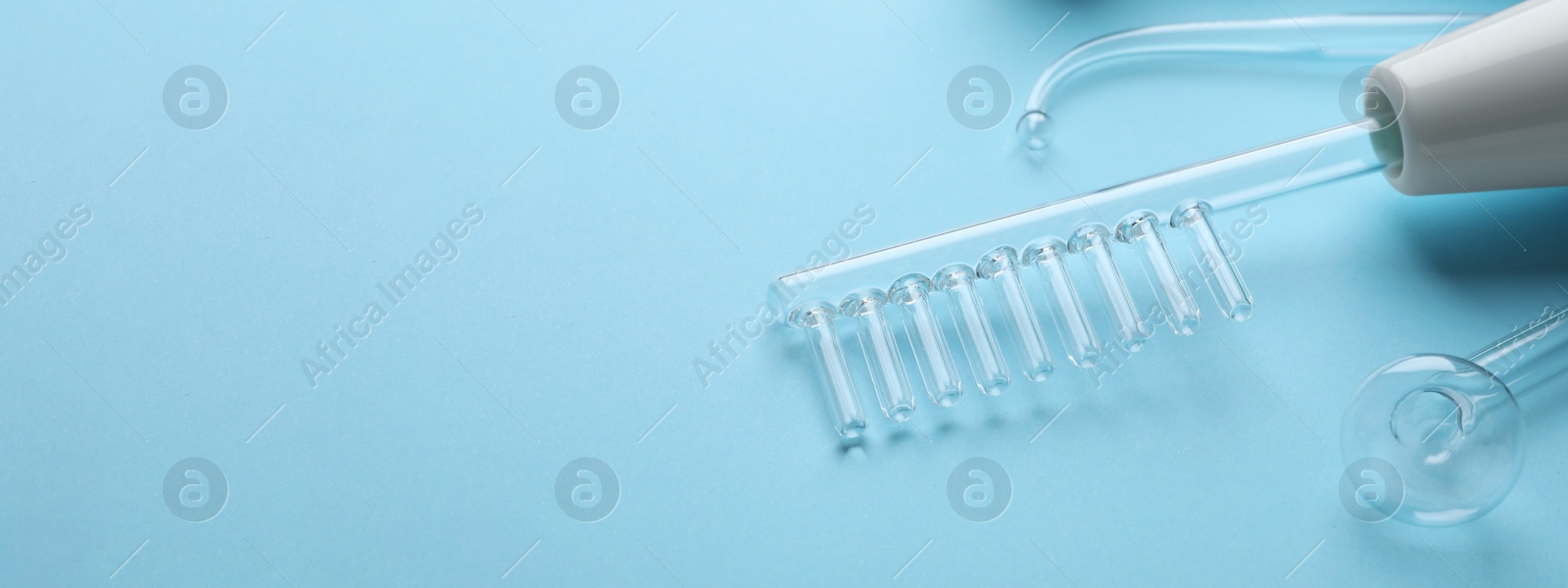 Image of High frequency darsonval device and different nozzles on light blue background, space for text. Banner design