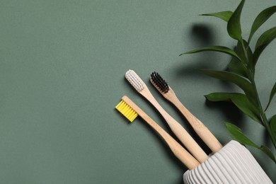 Photo of Toothbrushes and fresh leaves on green background, flat lay