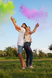 Photo of Happy couple with colorful powder dyes outdoors. Holi festival celebration
