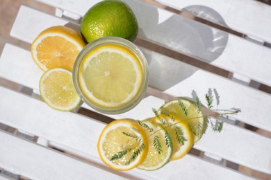 Delicious refreshing lemonade and pieces of citrus on white wooden table outdoors, flat lay