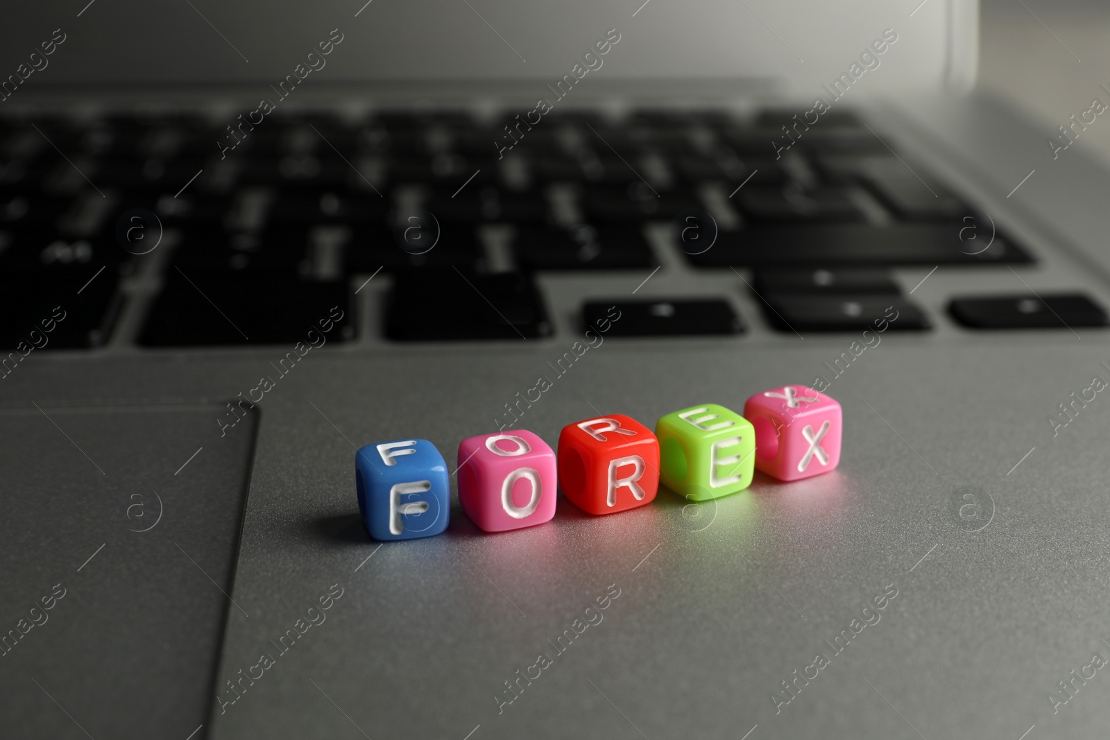 Photo of Word Forex made of colorful cubes with letters on laptop, closeup