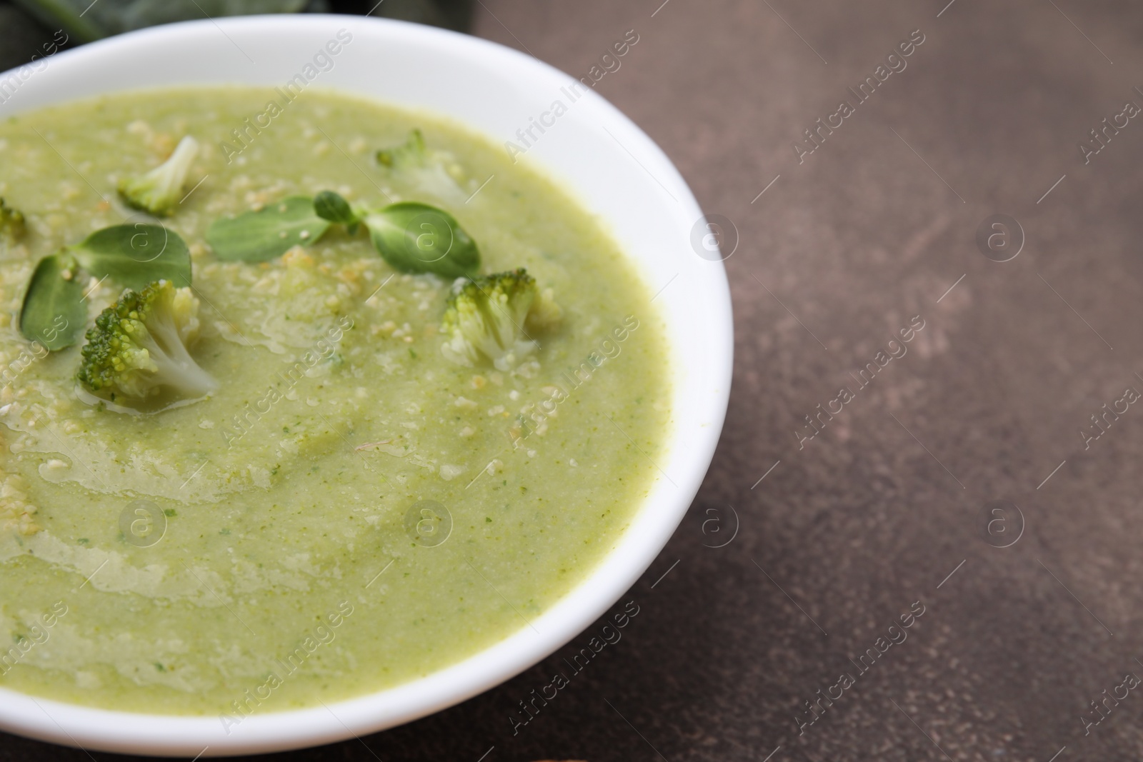 Photo of Delicious broccoli cream soup on grey table, closeup. Space for text