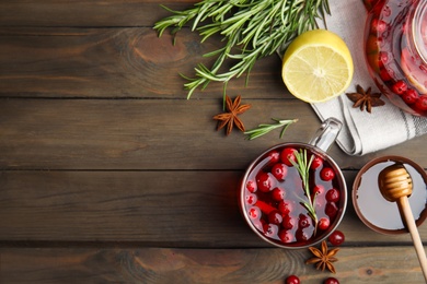 Photo of Tasty hot cranberry tea and fresh ingredients on wooden table, flat lay. Space for text