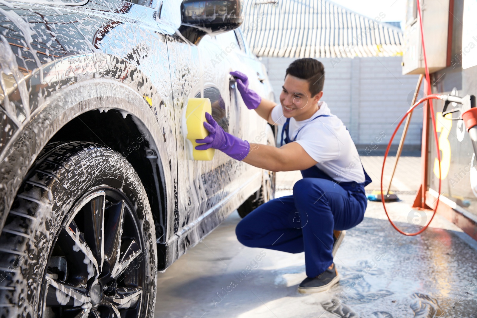 Photo of Worker cleaning automobile with sponge at car wash