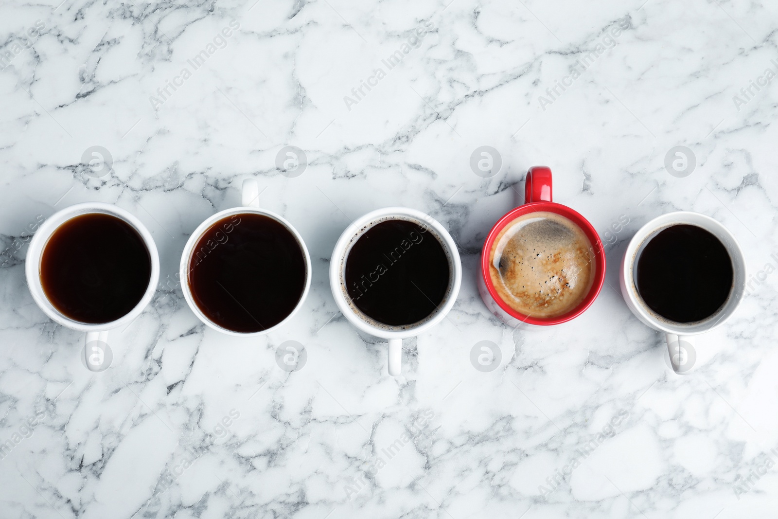 Photo of Cups of coffee and different one on marble background, top view