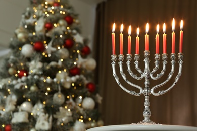 Silver menorah in room with Christmas tree, space for text