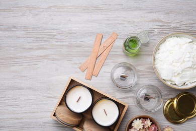 Flat lay composition with homemade candles 
and ingredients on light wooden background, space for text