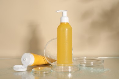 Photo of Wet face cleansing products and petri dishes on beige background