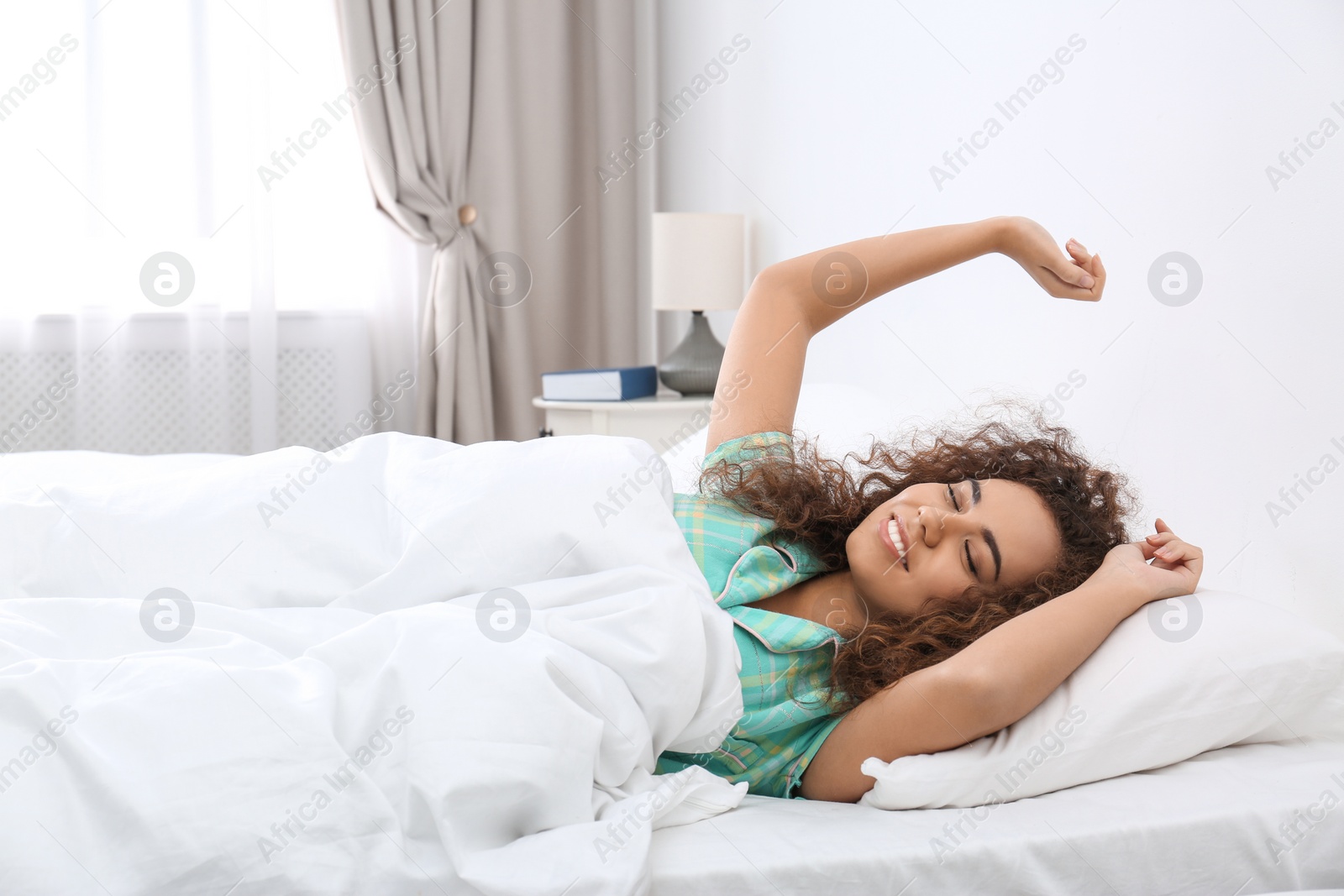Photo of Young African-American woman stretching at home. Bedtime
