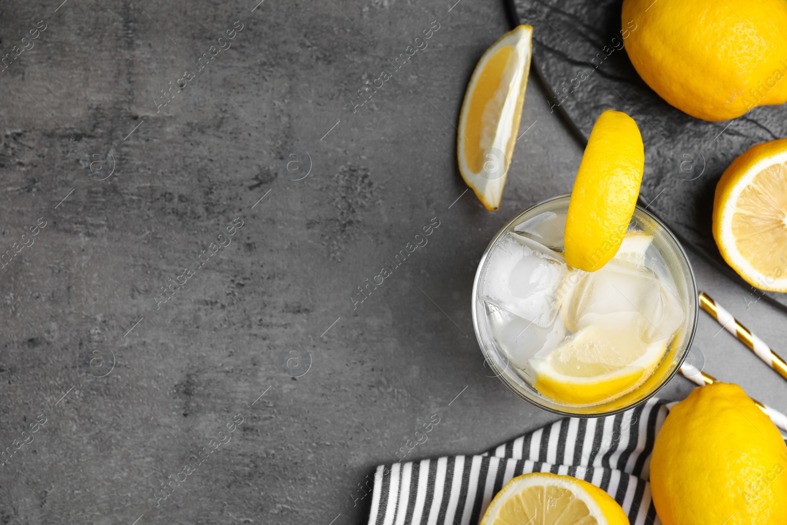 Photo of Soda water with lemon slices and ice cubes on grey table, flat lay. Space for text