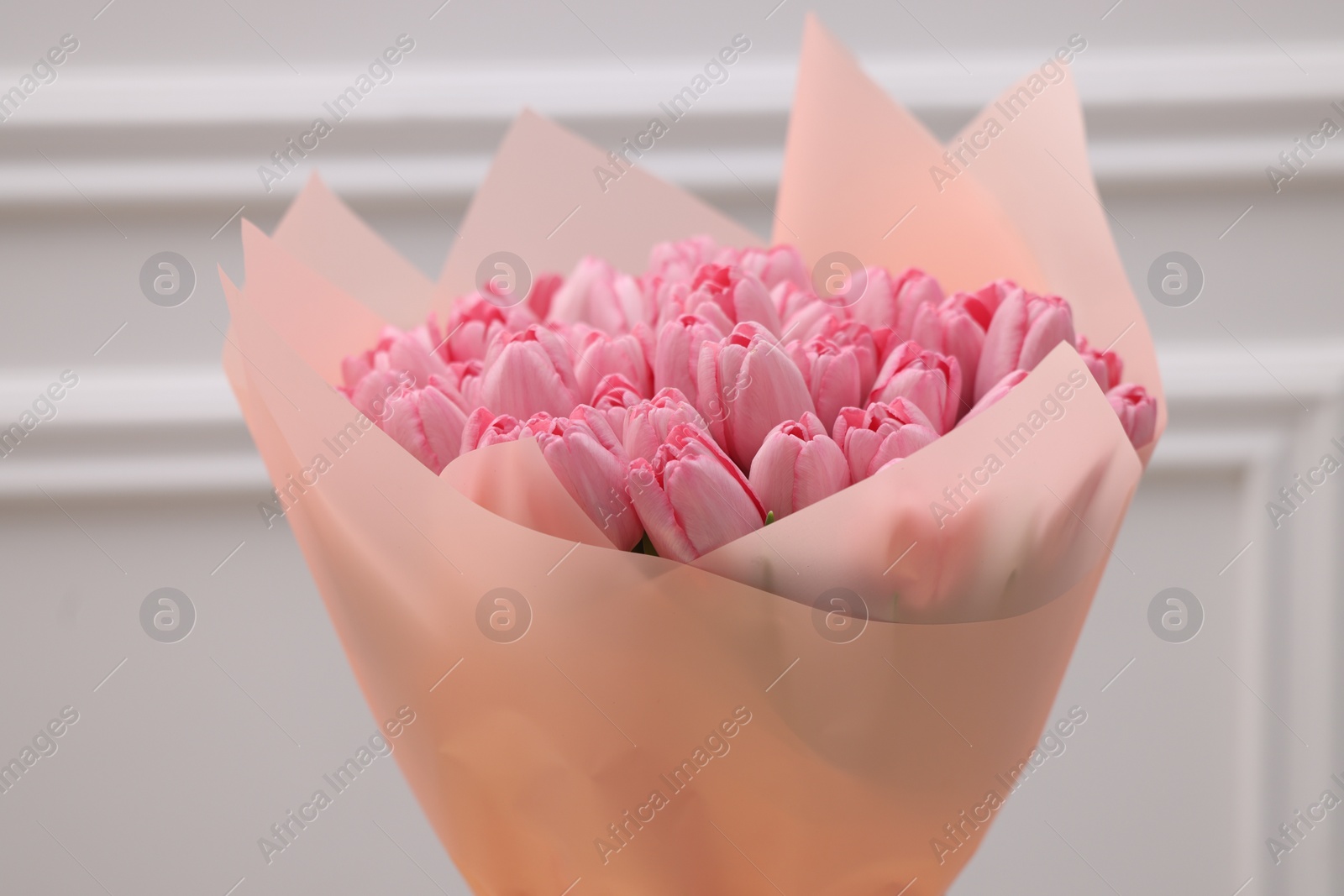 Photo of Bouquet of beautiful pink tulips near white wall, closeup