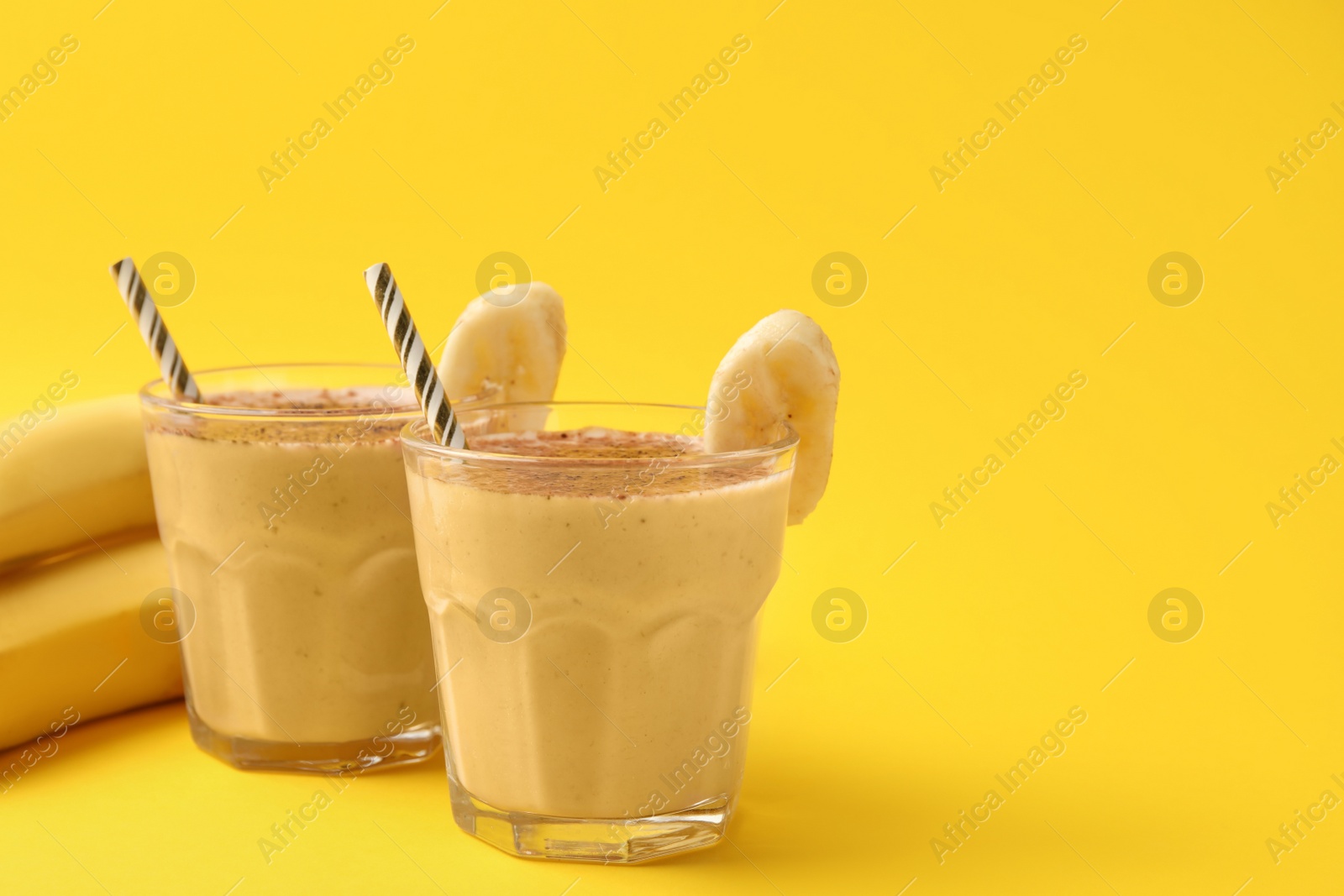 Photo of Tasty banana smoothie with chocolate and fresh fruits on yellow background. Space for text