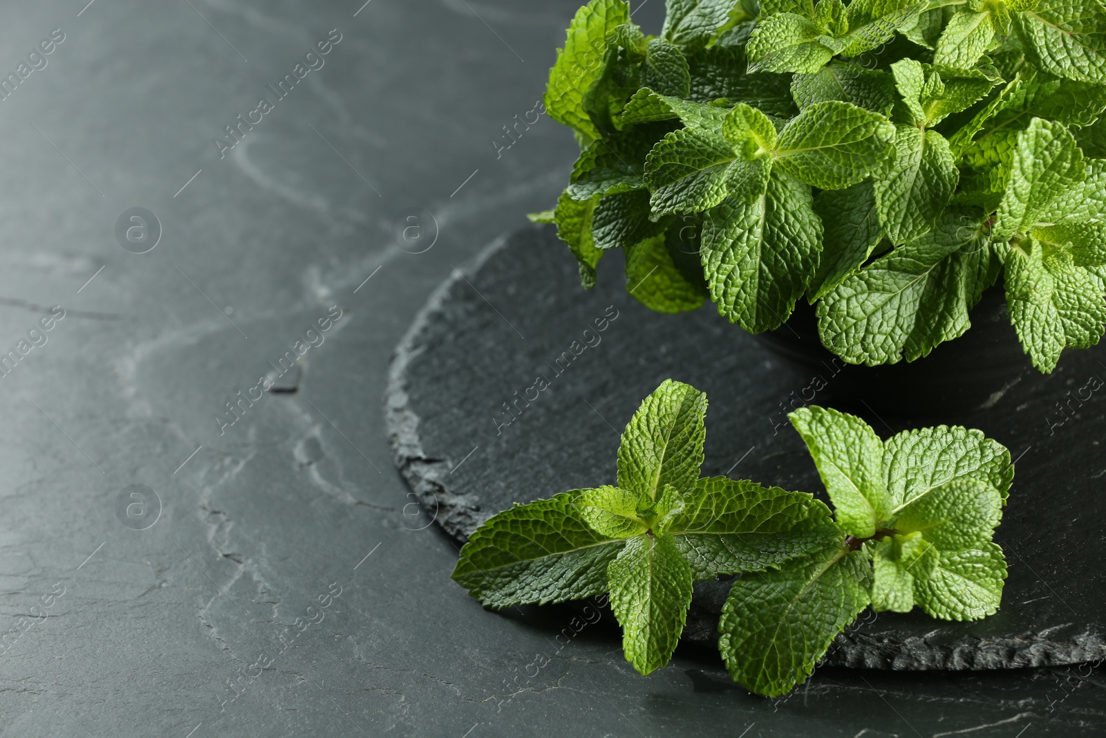 Photo of Fresh green mint leaves on black table, closeup. Space for text