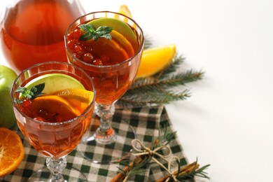 Photo of Christmas Sangria cocktail in glasses and ingredients on white table. Space for text
