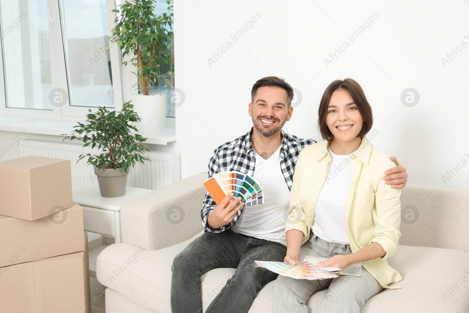 Photo of Happy couple choosing colors in new apartment. Moving day