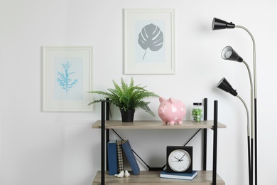 Photo of Shelving unit with decorative interior elements and piggy bank near white wall