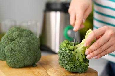 Photo of Woman cutting broccoli for smoothie at table, closeup