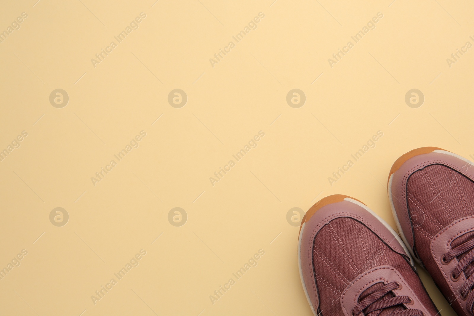 Photo of Pair of stylish kid's sneakers on beige background, top view. Space for text