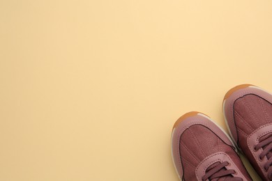 Photo of Pair of stylish kid's sneakers on beige background, top view. Space for text