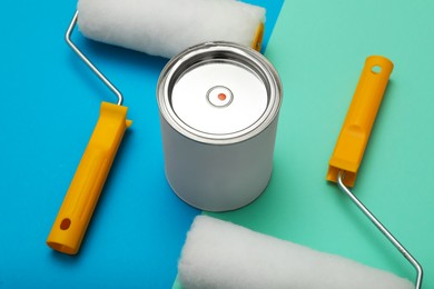 Photo of Can of orange paint and roller brushes on color background