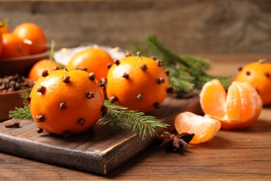 Photo of Delicious fresh tangerines with cloves on wooden table. Christmas celebration