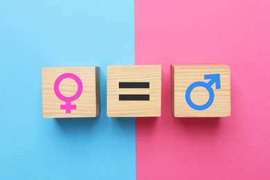Photo of Gender equality. Wooden cubes with equal, male and female signs on color background, flat lay