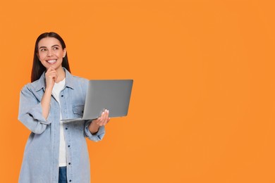 Photo of Thoughtful woman with laptop on orange background, space for text