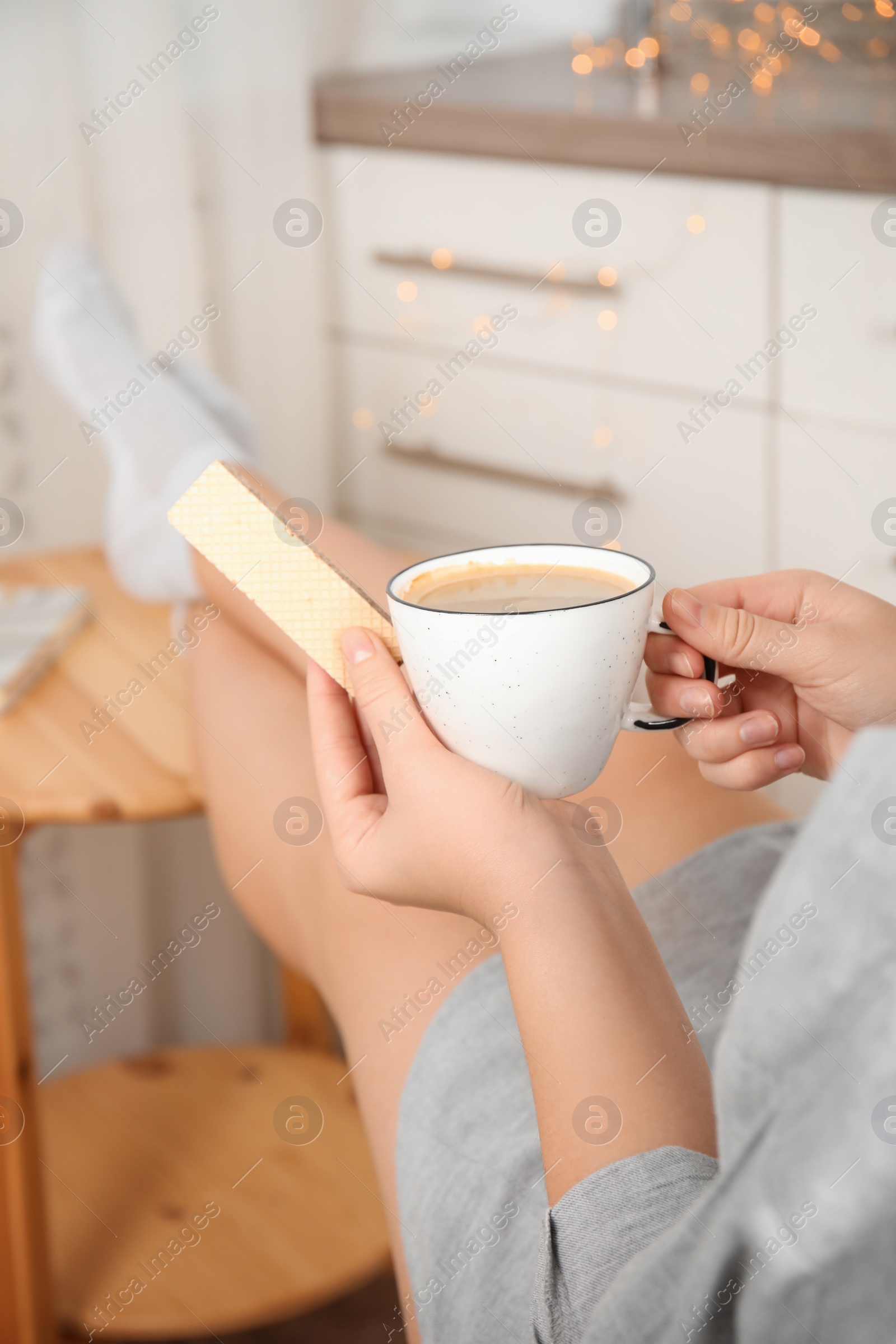 Photo of Woman having delicious wafer and coffee for breakfast indoors, closeup