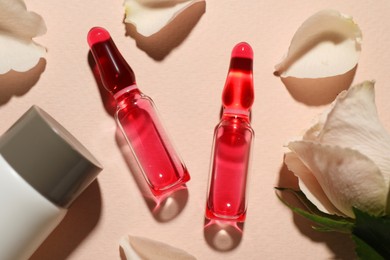 Pharmaceutical ampoules with medication, bottle and flower on pink background, flat lay