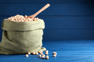 Photo of Raw chickpeas in bowl on blue wooden table. Space for text