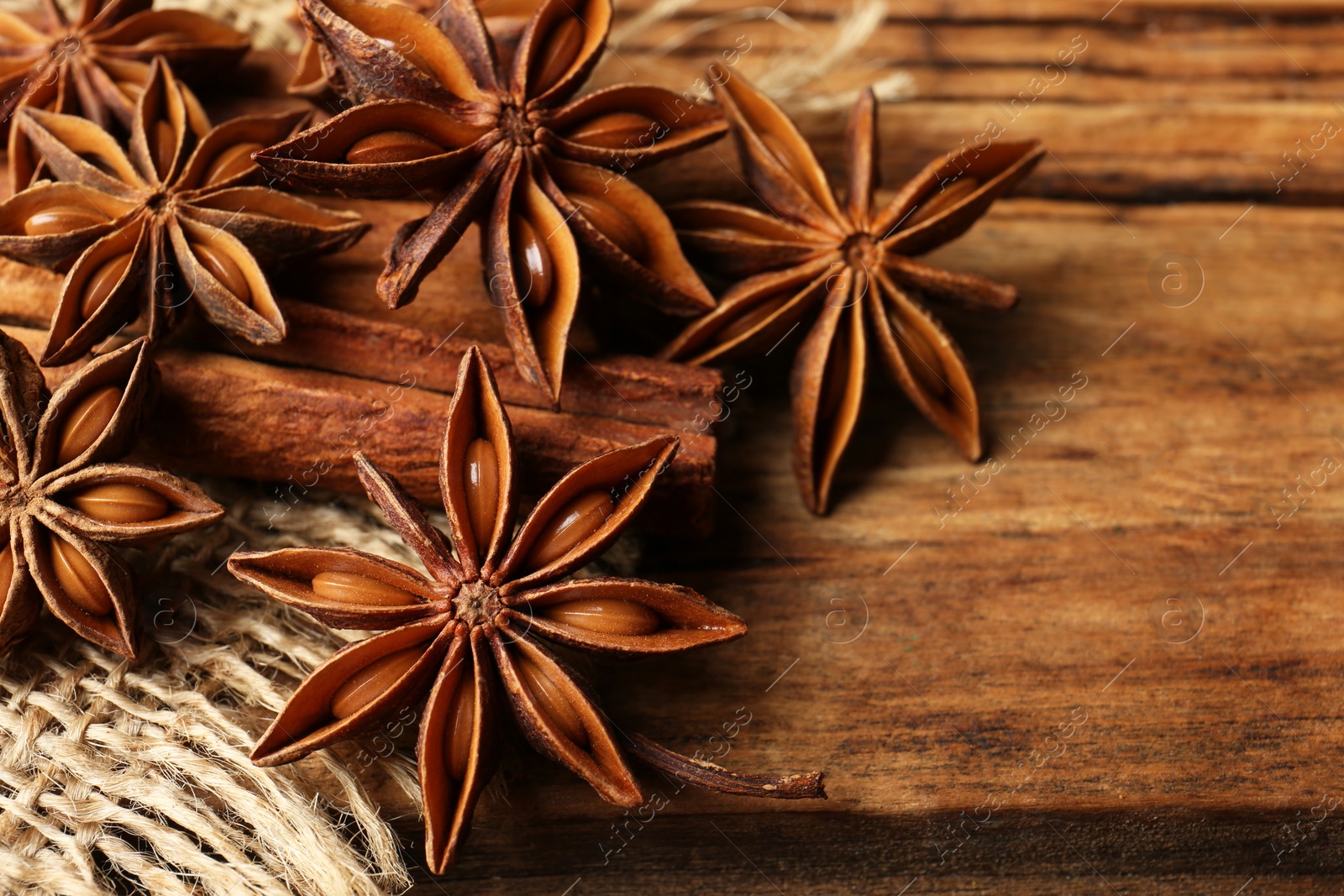 Photo of Aromatic anise stars and cinnamon sticks on wooden table, closeup