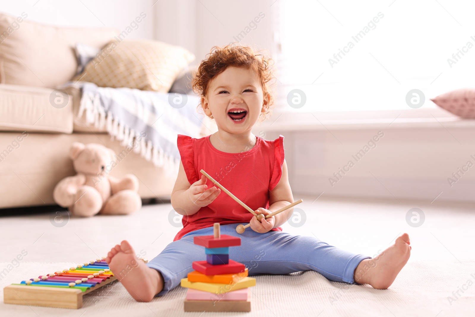 Photo of Cute little child playing with toys on floor at home