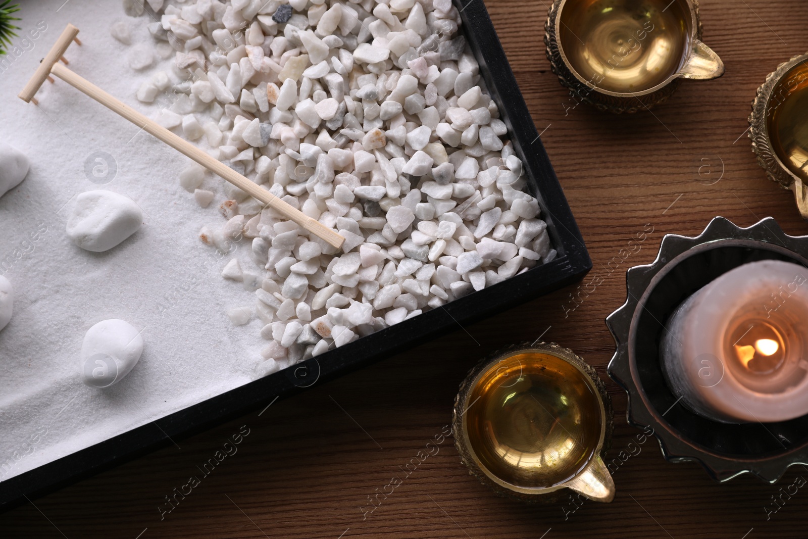 Photo of Beautiful miniature zen garden, candle and oil lamps on wooden table, flat lay