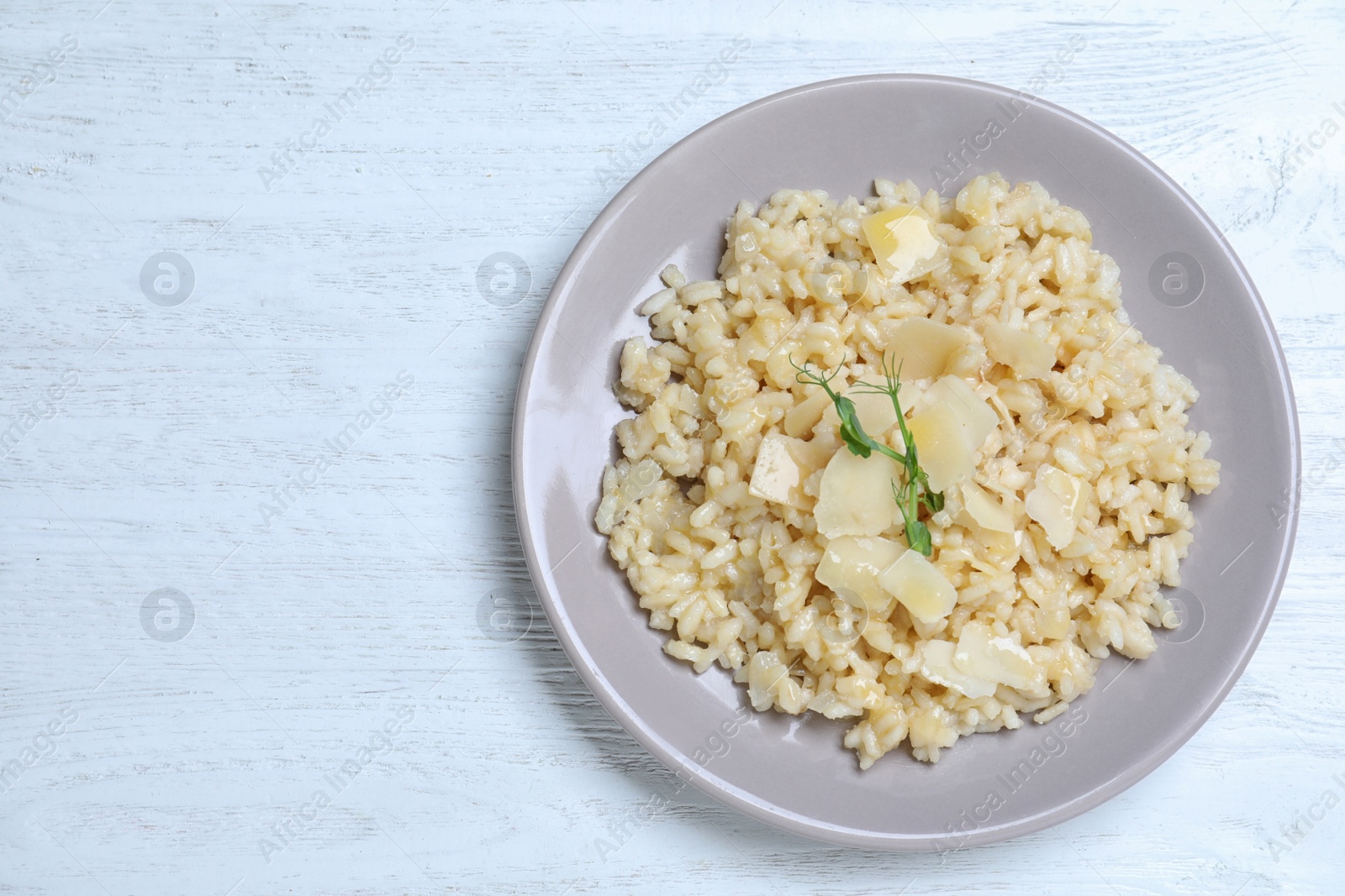 Photo of Delicious risotto with cheese on white wooden table, top view