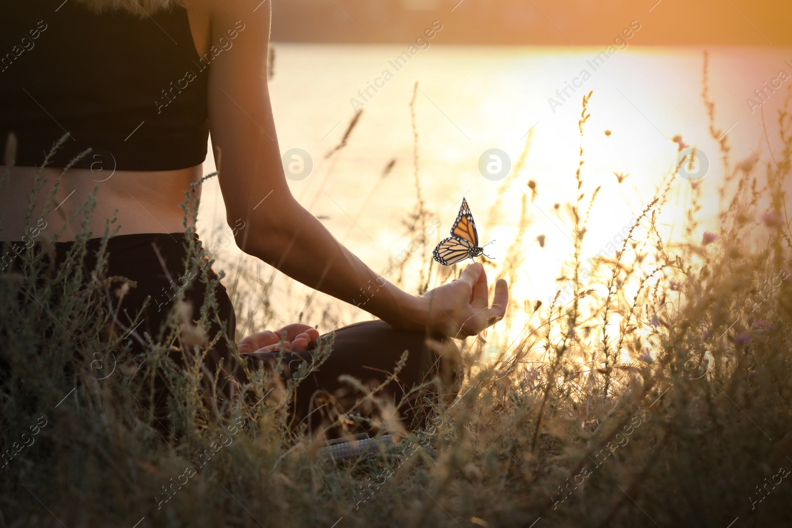 Image of Young woman meditating near river at sunset, closeup