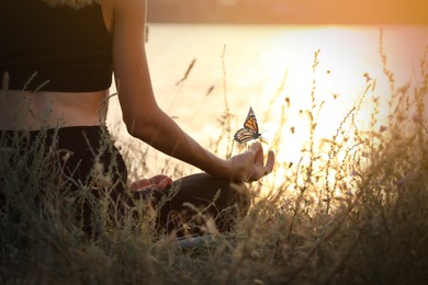 Young woman meditating near river at sunset, closeup